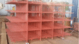 Red steel industrial rack with multi-level shelving inside a fabrication workshop.