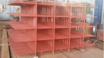 Red steel industrial rack with multi-level shelving inside a fabrication workshop.